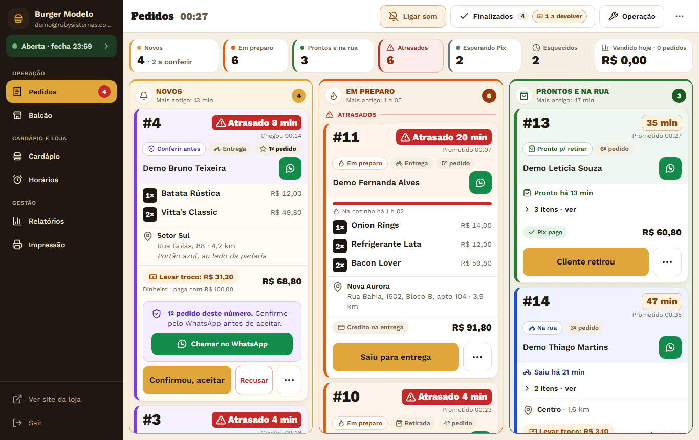 Painel de pedidos da loja de demonstração: colunas Novos, Em preparo e Prontos e na rua, com cartões de pedido mostrando itens, endereço, pagamento e os botões Aceitar, Saiu para entrega e Cliente retirou.